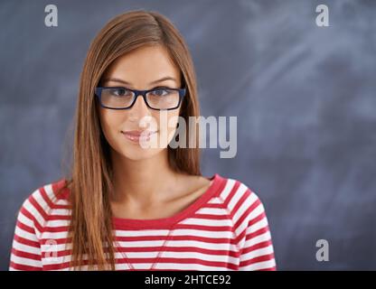 Sie kommt immer früh zu ihren Vorträgen. Porträt einer wunderschönen jungen Frau, die vor einer Tafel steht. Stockfoto