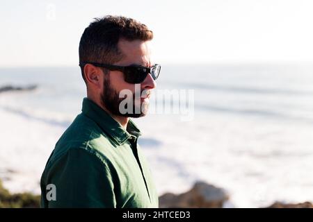 Portrait eines attraktiven Mannes in Sonnenbrillen am Meer, Konzept von Freizeit und Entspannung, Copy Space for Text Stockfoto