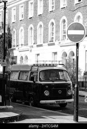 Vertikale Graustufenaufnahme eines VW-Wagens, der in der Nähe eines Stoppschilds im Chelsea-Viertel, London, Großbritannien, geparkt wurde Stockfoto