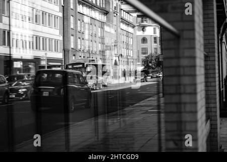 Graustufenaufnahme einer Spiegelung in Glas auf den Straßen von Westminster, London, Großbritannien Stockfoto