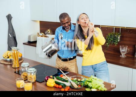 Filmisches Bild eines multiethnischen Seniorenpaares, das in der Küche Essen zubereitet. Drinnen Lifestyle-Momente zu Hause. Konzept über Dienstalter und Beziehungen Stockfoto
