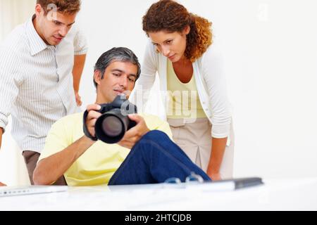 Fotografen, die Bilder in der Kamera betrachten. Männlicher Fotograf, der seinen Kollegen in seiner Kamera Bilder zeigt. Stockfoto