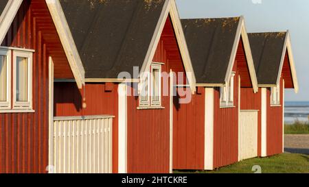 Holzhäuser mit roten Wänden und schwarzen Dächern in einem Meer Stockfoto