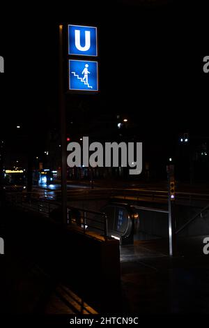 Eine vertikale Aufnahme des U-Bahnhofes mit dem Symbol für die Treppe in München, Deutschland, während der Nacht Stockfoto