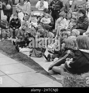 Laing Sports Ground, Rowley Lane, Elstree, Barnett, London, 11/06/1988. Ein kleines Mädchen, das vom Publikum der Kinder und ihrer Eltern auf die Punch &amp; Judy Show beim Familientag 1988 auf dem Laing's Sports Ground zeigt. Zu den Attraktionen des diesjährigen Familientages gehörten eine Parade mit Oldtimern, Hubschrauberflüge, Plattenschlagen, Stände, ein Wettbewerb im Stil „IT's a Knockout“ sowie Tennis- und Fußballturniere mit sechs Spielern. Eröffnet wurde die Veranstaltung von John Conteh, dem ehemaligen Weltmeister im Leichtgewicht, und endete mit einem Barbecue und einer Disco. Dieses Foto erschien in der Ausgabe August 1988 von Team Stockfoto