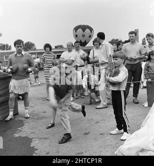 Laing Sports Ground, Rowley Lane, Elstree, Barnett, London, 20/06/1987. Ein Junge, der beim Familientag 1987 auf dem Laing's Sports Ground einen Wurf auf die Kokosnuss wirft. Zu den Attraktionen des diesjährigen Familientages gehörten Fahrten mit dem Heißluftballon, Hubschrauberflüge, eine Hüpfburg und ein Festplatz, Stände, ein Wettbewerb im „IT's a Knockout“-Stil sowie Tennis- und Fußballturniere mit sechs Spielern. Cast-Mitglieder aus Ostenders traten zu Gast auf und traten in den Fußball-Wettbewerb ein. Stockfoto