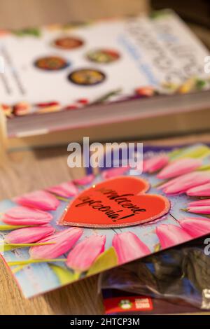 Geburtstagskarte mit Herz und Blumen neben einem Buch. Stockfoto