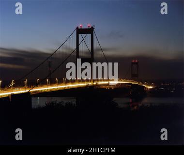 Severn Bridge, M48, Aust, South Gloucestershire, 10/11/1987. Die Severn-Brücke leuchtet nachts, während der von Laing geleisteten Verstärkungsarbeiten gesehen. Das ursprüngliche Design und der Bau der Severn-Brücke hatten das erhöhte Verkehrsaufkommen seit ihrer Fertigstellung im Jahr 1966 unterschätzt, und obwohl es auf eine Lebensdauer von 120 Jahren gebaut wurde, wurde festgestellt, dass bereits nach 20 Sanierungsarbeiten erforderlich waren. Laing Industrial Engineering &amp; Construction gewann den &#XA3;29,5m-Vertrag vom Ministerium für Verkehr und Stärkung der Arbeit an allen Elementen der Struktur begann im Mai 1987. Das Projekt wurde im April 1990 in t abgeschlossen Stockfoto