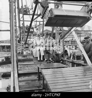 Skegness, East Lindsey, Lincolnshire, 22/05/1954. Ein Paar, das auf einem Riesenrad unterwegs war, während eines Laing-Staff-Trips nach Skegness. Im Jahr 1947, nach einer siebenjährigen Pause, hatte Laing seine „Ausflüge in die Umgebung“ für Mitarbeiter und ihre Familien wiederbelebt, wobei die Reisen im Mai und Juni stattfinden. Im Jahr 1954 waren sieben Ausflüge geplant, die über fünf Wochen im Mai und Juni stattfinden sollen. Diese Reise nach Skegness war für Mitarbeiter und ihre Familien aus den Midlands und South Yorkshire. Stockfoto