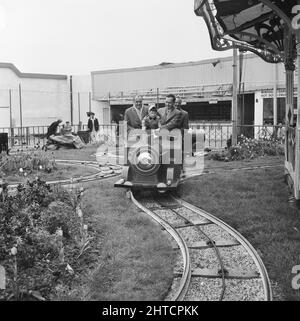 Skegness, East Lindsey, Lincolnshire, 22/05/1954. Drei Männer begleiten ein kleines Kind auf einem Miniatureisenbahnmotor während einer Laing-Mitarbeiterreise nach Skegness. Im Jahr 1947, nach einer siebenjährigen Pause, hatte Laing seine „Ausflüge in die Umgebung“ für Mitarbeiter und ihre Familien wiederbelebt, wobei die Reisen im Mai und Juni stattfinden. Im Jahr 1954 waren sieben Ausflüge geplant, die über fünf Wochen im Mai und Juni stattfinden sollen. Diese Reise nach Skegness war für Mitarbeiter und ihre Familien aus den Midlands und South Yorkshire. Stockfoto