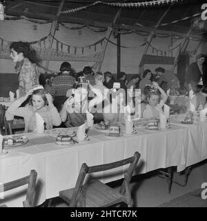 Thurleigh Airfield, Thurleigh, Bedfordfordshire, 19/12/1953. Eine Gruppe von Mädchen, die ihre Partyhüte auf einer Kinderparty anpassen. Dieses Foto zeigt eine Kinderparty, die von Laings Wohlfahrtspersonal und Mitgliedern des Komitees für die Kinder von Mitarbeitern organisiert wurde, die am Thurleigh Airfield-Projekt arbeiten. Die Party fand im Camp Theatre statt und beinhaltete Clowns, Spiele, eine Filmshow, Geschenke vom Weihnachtsmann und Tee für sechzig Kinder. Stockfoto