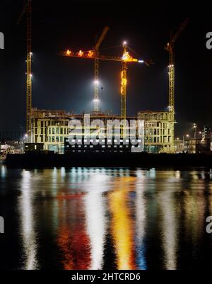 Vauxhall Cross, Albert Embankment, Vauxhall, Lambeth, London, 03/12/1990. Ein Blick über die Themse bei Nacht während des Aufbaus des Vauxhall Cross, der einen der Kraniche vor Ort zeigt, der mit beleuchteten Weihnachtsdekorationen geschmückt ist. Vauxhall Cross, auch bekannt als SIS oder MI6 Building, wurde vom Architekten Terry Farrell entworfen und von Laing Management Contracting für Regalian Properties gebaut. Es wurde an die Regierung verkauft und wurde zum Hauptsitz des britischen Geheimdienstes oder MI6. Laing erhielt den Zuschlag für das Gebäude im Jahr 1989, mit dem Baubeginn Stockfoto