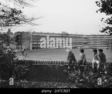 Victoria Park Estate, Macclesfield, Heshire East, Heshire, 18/04/1968. Vier Jungen, die auf einer Steinmauer sitzen und in der Ferne auf die Wohnungen des Victoria Park blicken, das mit dem 12M Jespersen-System gebaut wurde. Im Jahr 1963 kauften John Laing und Son Ltd die Rechte an dem dänischen industrialisierten Bausystem für Wohnungen, die als Jespersen (manchmal auch als Jesperson bezeichnet) bekannt sind. Das Unternehmen baute Fabriken in Schottland, Hampshire und Lancashire, in denen Jespersen Fertigteile und Betonfertigteile produzierte, wodurch der Wohnungsbau rationalisiert werden konnte und Zeit und Geld eingespart wurde. Der Victo Stockfoto