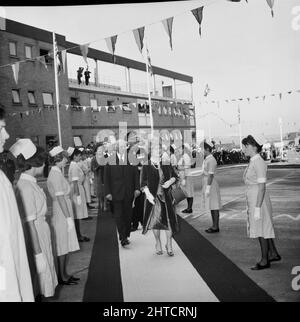 West Cumberland Hospital, Homewood Road, Homewood, Whitehaven, Copeland, Cumbria, 21/10/1964. Die Queen Mother und ihr Gefolge nähern sich dem Eingang des West Cumberland Hospital zur offiziellen Eröffnung. Der Prozessionsweg wird von Krankenschwestern und anderen Krankenhauspersonal flankiert. Stockfoto