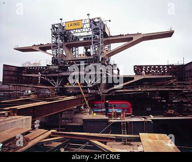 Westway Flyover, A40, Paddington, City of Westminster, London, 17/09/1969. Der Transporterkran senkt eine Deckeinheit des Westway Flyover an ihren Platz, während er die Great Western Road überspannt. Der Transporterkran wurde speziell von der Laing-Werksabteilung entworfen und gebaut. Die vierbeinige Gantry machte 400 Fahrten entlang der Fahrbahn von Abschnitt 5, hob die einzelnen Decks vom Ende der Harrow Road an, transportierte sie auf der Länge der Autobahn und senkte sie in Position. Die Deckseinheiten für Abschnitt 5 wiegen bis zu 130 Tonnen und sind mehr als 28 Meter breit und tragen alle sechs Spuren des Einlegens Stockfoto