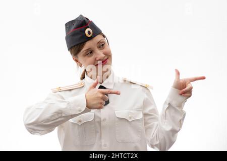 Schöne junge weibliche russische Polizist in Kleideruniform zeigt Schilder mit ihren Händen auf weißem Hintergrund. Selektiver Fokus. Hochformat Stockfoto