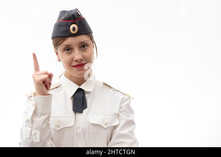 Schöne junge weibliche russische Polizist in Kleideruniform zeigt Schilder mit ihren Händen auf weißem Hintergrund. Selektiver Fokus. Hochformat Stockfoto