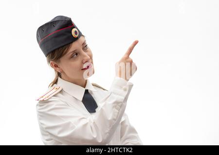 Schöne junge weibliche russische Polizist in Kleideruniform zeigt Schilder mit ihren Händen auf weißem Hintergrund. Selektiver Fokus. Hochformat Stockfoto