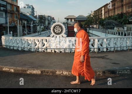 Ein orangefarbener buddhistischer Mönch, der über die Charoenrat 31 Bridge, eine lang (Kanal) Brücke in Bangkok, Thailand, fährt Stockfoto