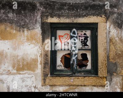 Verwitterte Hausfassade mit Gemälden auf kaputten Fenstern in Lissabon, Portugal Stockfoto