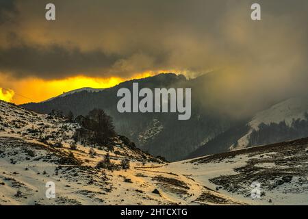 Goldene Lichter bei Sonnenuntergang auf den schneebedeckten Gipfeln der Abruzzen. Wolkiger Himmel. Roccaraso, Provinz L'Aquila, Abruzzen, Italien, Europa Stockfoto