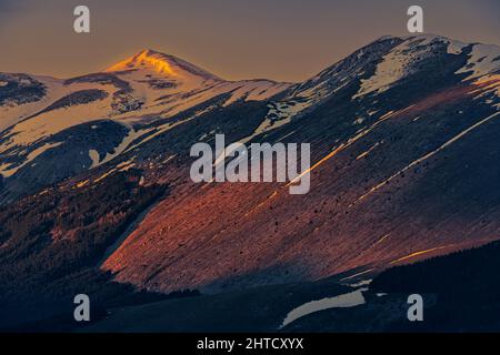 Goldene Lichter bei Sonnenuntergang auf den schneebedeckten Gipfeln der Abruzzen. Wolkiger Himmel. Roccaraso, Provinz L'Aquila, Abruzzen, Italien, Europa Stockfoto