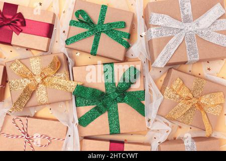 Geschenke gebunden mit bunten Bändern auf goldenem Hintergrund mit Konfetti. Konzept für den Boxtag. Stockfoto