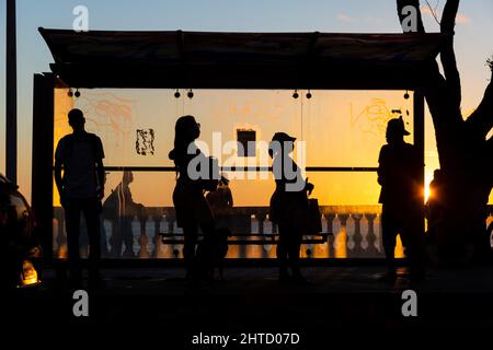 Silhouette von Menschen, die an der Bushaltestelle am Rande von Porto da Barra in Salvador, Brasilien, warten Stockfoto