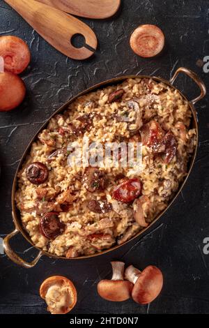 Risotto ai funghi, Pilzreis, mit Zutaten, Top Shot auf dunklem Hintergrund Stockfoto