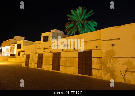 Eine Palme, die hinter Geschäften auf dem Nachtmarkt (in arabischer suq ellil) in Yanbu Saudi-Arabien sitzt Stockfoto