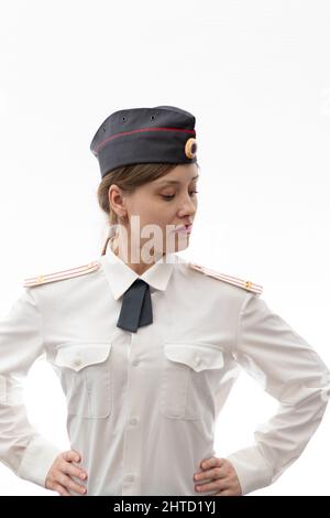 Eine schöne junge russische Polizist in Uniform in einer Mütze und Schultergurten eines Oberstleutnants und einem weißen Hemd auf einem weißen Bac Stockfoto
