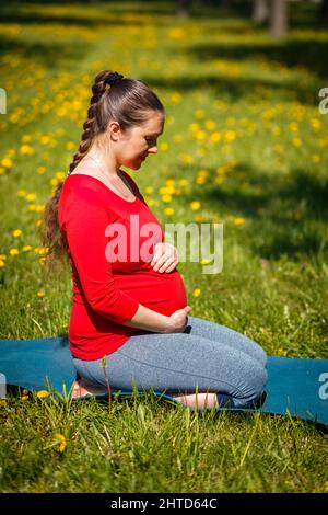 Schwanger Frau tun Asana Virasana Held Pose auf den Knien im Freien Stockfoto