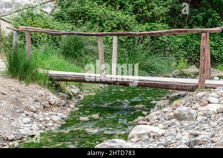 Eine kleine Holzbrücke über einen Mineralstrom, die von der Mineralwasserquelle Bagni San Filippo aus beginnt Stockfoto