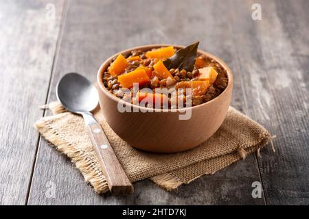 Linsen-Eintopf mit Kürbis und Karotte in einer Schüssel auf einem Holztisch Stockfoto