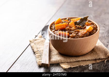 Linsen-Eintopf mit Kürbis und Karotte in einer Schüssel auf einem Holztisch Stockfoto