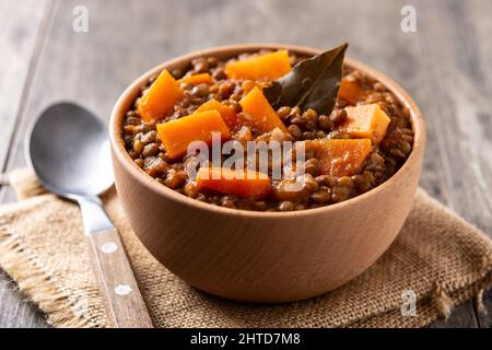 Linsen-Eintopf mit Kürbis und Karotte in einer Schüssel auf einem Holztisch Stockfoto