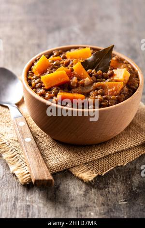 Linsen-Eintopf mit Kürbis und Karotte in einer Schüssel auf einem Holztisch Stockfoto