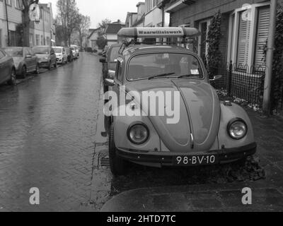 Graustufenaufnahme eines alten Volkswagen Beetle, der auf der Straße in Bussum, Niederlande, geparkt wurde Stockfoto