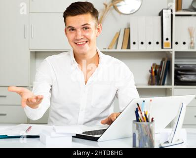 Kerl in weißem Hemd arbeitet im Büro und lächelt Stockfoto