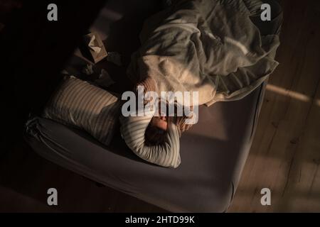 Overhead-Ansicht einer traurigen Frau, die an mehreren Persönlichkeitsstörungen im Bett liegt. Stockfoto