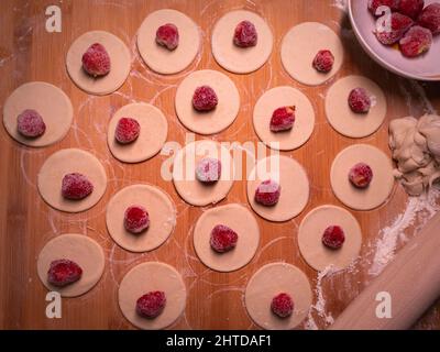 Knödel Teig mit Erdbeeren, schneiden Stücke von Teig und Erdbeerfrucht warten auf Verpackung kleben Stockfoto