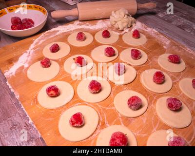 Knödel Teig mit Erdbeeren, schneiden Stücke von Teig und Erdbeerfrucht warten auf Verpackung kleben Stockfoto