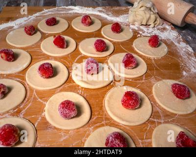 Knödel Teig mit Erdbeeren, schneiden Stücke von Teig und Erdbeerfrucht warten auf Verpackung kleben Stockfoto