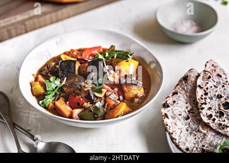 Aubergine mit Karotte, Paprika und Kirschtomaten Sauce Paprika und Kirschtomaten Sauce mit Purple Sweet Potato Tortilla Stockfoto