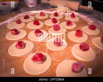 Knödel Teig mit Erdbeeren, schneiden Stücke von Teig und Erdbeerfrucht warten auf Verpackung kleben Stockfoto