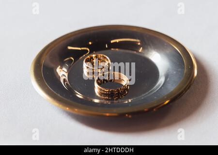 Zwei goldene Eheringe auf einer Metallplatte Stockfoto