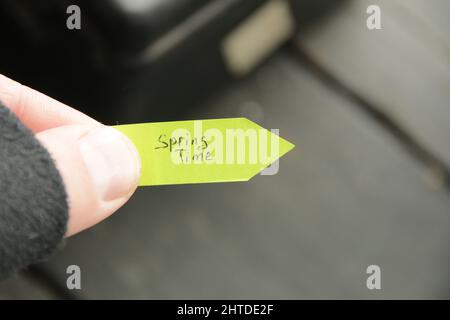 Frühling. Die Hand hält einen Anhänger mit einer handschriftlichen Inschrift. Stockfoto