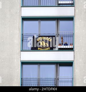Berlin, 26. Februar 2022: Fenster in einer Wohnung in einem Fertighaus mit einem Plakat zur Aufnahme von Flüchtlingen und ihren Familien Stockfoto