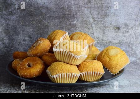Eine Nahaufnahme von Muffins und Donuts auf einem schwarzen Teller Stockfoto