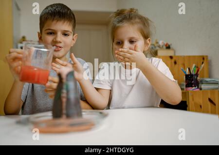 Kinder, Junge und ein Mädchen führen zu Hause ein Experiment mit einem Vulkanausbruch durch. Stockfoto